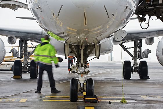 Worker standing by airplane on runway